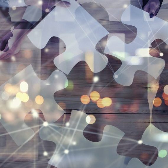 Business people join puzzle pieces in a modern office. Concept of teamwork and partnership. double exposure with internet network effects